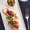 Bruschetta with Parma and goat cheese, olives and almonds. Wine set. Toned image.