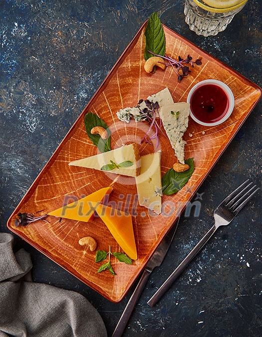 Cheese plate with nuts and jam. Plate with different types of cheeses.