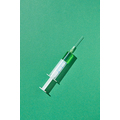 Green vaccine or serum in plastic syringe 20 ml for an intravenous injection on a light green background with hard shadow, copy space.