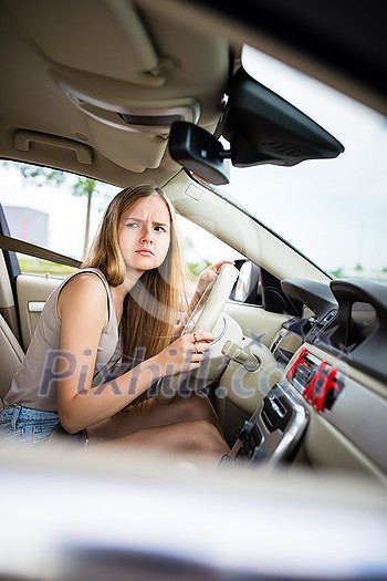 Cute female teen driver enjoying her freshly acquired driving license at the wheel of her first car