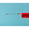 Red liquid or blood in plastic syringe with droplet on the needle on a pastel blue background, copy space.