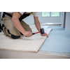 professional carpenter using rubber hammer while installing new laminated wooden floor in a unfinished apartment