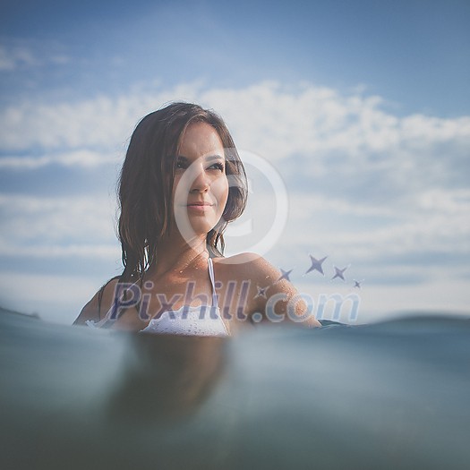 Pretty, young woman enjoying a day at the beach, relaxing on inflatable mattress