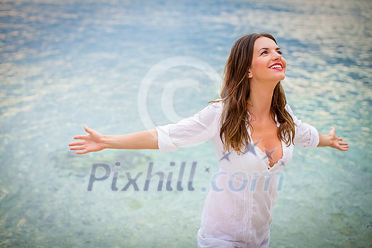 Woman relaxing at the beach with arms open enjoying her freedom,  independence, good health, time off.