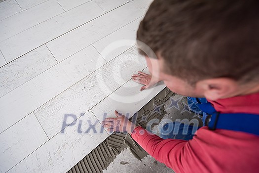 skilled worker installing the ceramic wood effect tiles on the floor Worker making laminate flooring on the construction site of the new apartment skilled worker installing the ceramic wood effect tiles on the floor Worker making laminate flooring on the construction site of the new apartment