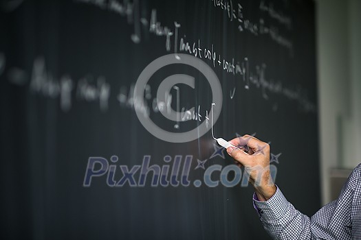 Math teacher by the blackboard during mathclass - detail of the hand with chalk Math teacher by the blackboard during mathclass - detail of the hand with chalk