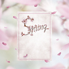 Cherry blossom letters on a vintage paper card with floating petals on soft pink spring nature backgound.