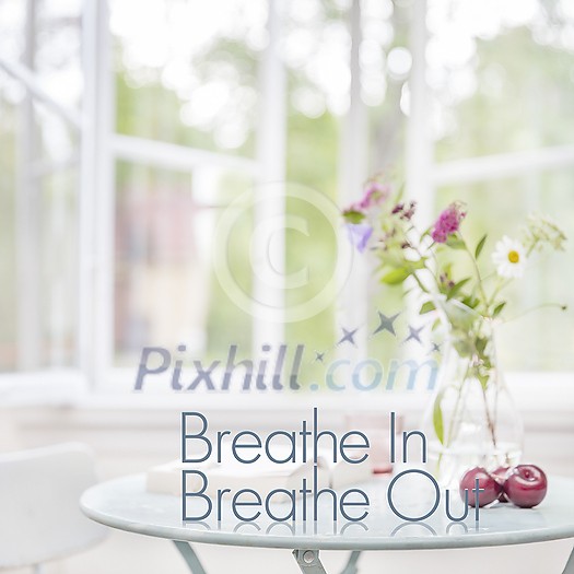 3d Breathe In Breathe Out Text on small living room side table in light soft home environment with windows open.