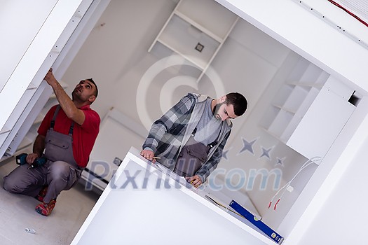 two professional workers installing a new stylish modern kitchen furniture two professional workers installing a new stylish modern kitchen furniture