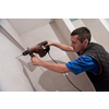 young professional construction worker drilling holes in the bathroom wall for installing bathroom accessories