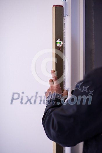 male worker carpenters using level tool while installing interior door at new luxury apartment male worker carpenters using level tool while installing interior door at new luxury apartment