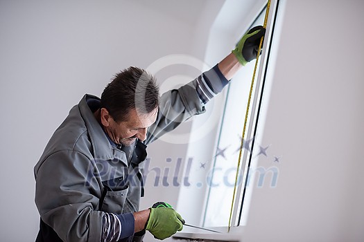 service man installing window with measure tape Man measuring window before installation of roller shutter