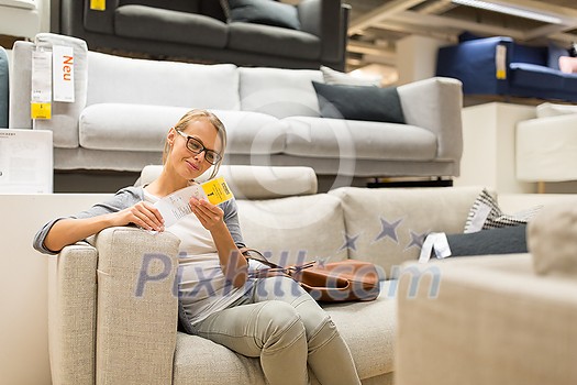 Pretty, young woman choosing the right furniture for her apartment in a modern home furnishings store (color toned image; shallow DOF) Pretty, young woman choosing the right furniture for her apartment in a modern home furnishings store (color toned image; shallow DOF)