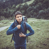 Young man in the mountains during an outdoor advernture/expedition, zipping his jacket as the evening cold is setting in