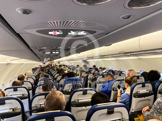 Cabin of a modern airplane filled with passangers to its full capacity during flight, after delayed departure (shallow DOF)