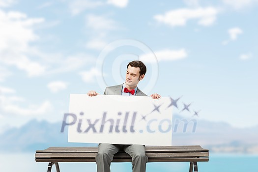 Young man sitting on bench with white banner Young man sitting on bench with white banner