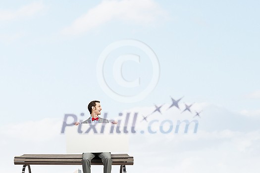 Young man sitting on bench with white banner 
