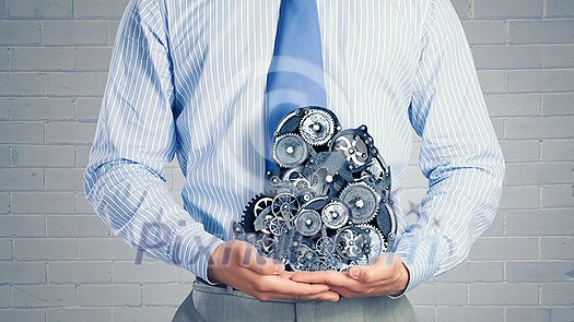 Close up of businessman in suit holding metal gears in hands Close up of businessman in suit holding metal gears in hands