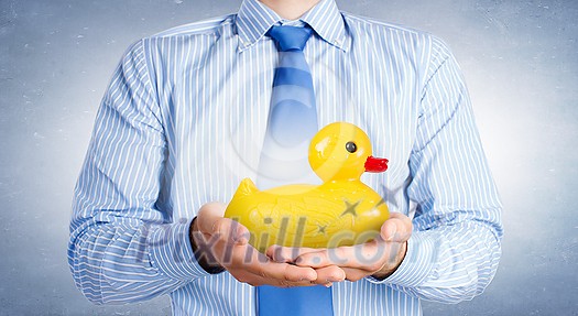 Businessman holding in hands yellow toy rubber or plastic duck Businessman holding in hands yellow toy rubber or plastic duck