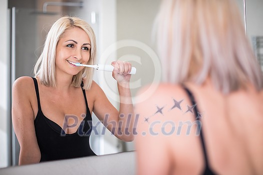 Pretty, middle aged woman brushing her teeth in a modern design bathroom Pretty, middle aged woman brushing her teeth in a modern design bathroom