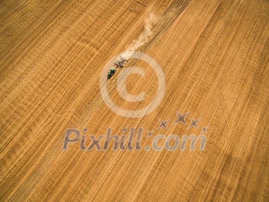 Aerial view of a tractor working a field after harvest