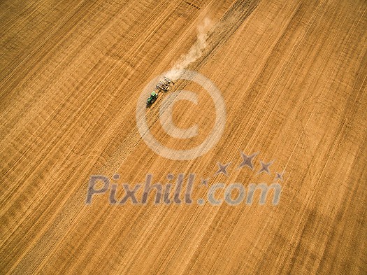 Aerial view of a tractor working a field after harvest Aerial view of a tractor working a field after harvest