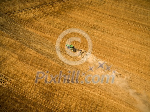 Aerial view of a tractor working a field after harvest