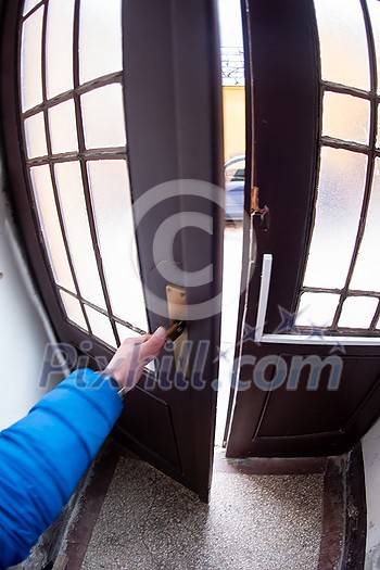 the man in the blue jacket opening door of a building to get out the man in the blue jacket opening door of a building to get out