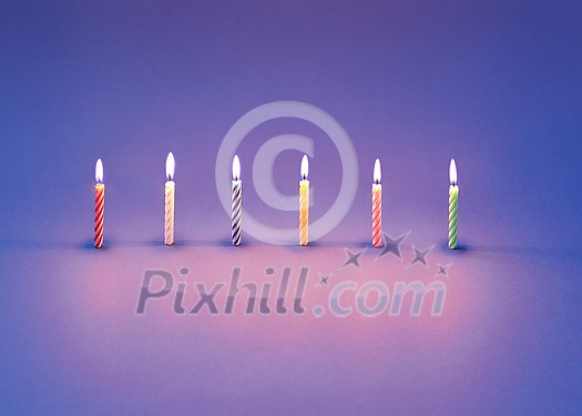 Greeting card from burning candles for sweet dessert and cakes on a violet background with light reflection and soft shadows, copy space. Greeting card from burning candles for sweet dessert and cakes on a violet background with light reflection and soft shadows, copy space.