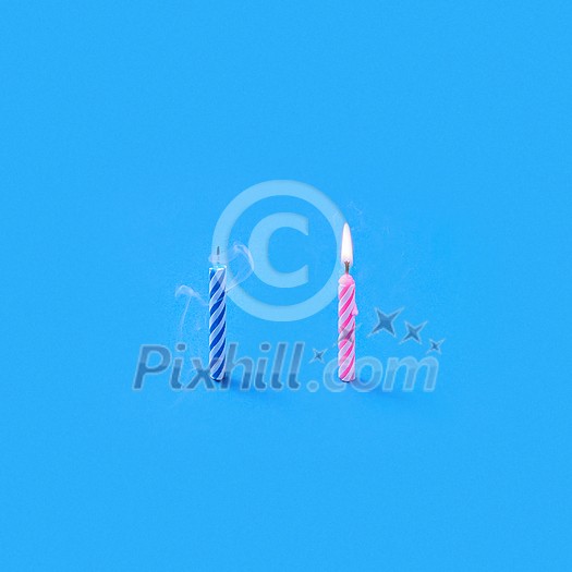 Holiday candles for sweet cake one burning and another is blown out on a blue background with copy space. Birthday party card composition Holiday candles for sweet cake one burning and another is blown out on a blue background with copy space. Birthday party card composition