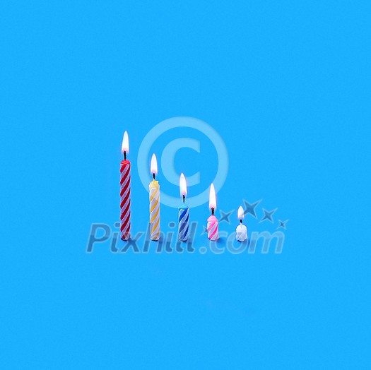 Greeting birthday card from vertically standing candles of different height for sweet dessert and cakes on blue background with soft shadows, copy space. Greeting birthday card from vertically standing candles of different height for sweet dessert and cakes on blue background with soft shadows, copy space.
