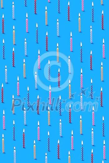 Decorative congratulation composition from multicolored bithday candles for sweet dessert on a blue background. Birthday party card.