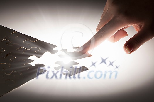 Hand connecting missing jigsaw glowing puzzle piece Hand connecting missing jigsaw glowing puzzle piece