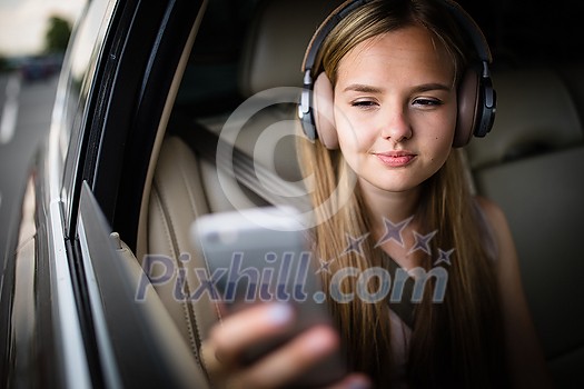 Cute teenage girl in a car, enjoying the ride - looking for the best possible data coverage for her phone