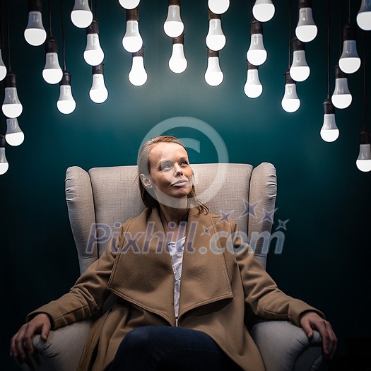 Pretty, young woman having so many ideas for business ventures - light bulb illumination/eureka moment concept image (color toned image)
