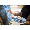 Palette and paint brush in artist hands. Artist paints oil picture with paint brush in hand palette close-up. Artist painting holding palette and paint brush in hand. Artists paintbrush with palette.