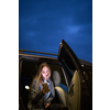 Young woman with her cell phone sitting in the backseat of a car, getting ready to travel (color toned image; shallow DOF)