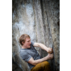 A rock climber climbing on a boulder rock outdoors. Group of friends involved in sports outside.