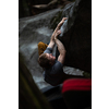 A rock climber climbing on a boulder rock outdoors. Group of friends involved in sports outside.