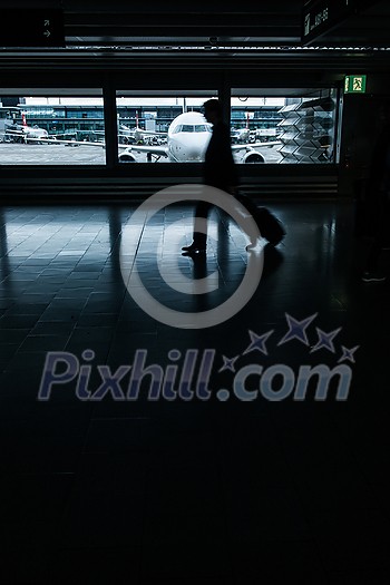 Airport rush: people with their suitcases walking along a corridor (motion blurred image; color toned image)