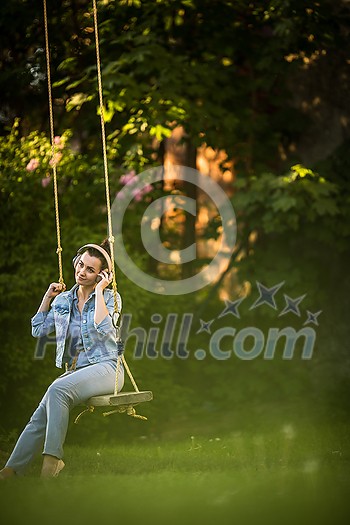 Pretty, young woman with headphones outdoors, in a lovely park, enjoyig the hi-fi quality sound, listening to her favorite songs (color toned image) Pretty, young woman with headphones outdoors, in a lovely park, enjoyig the hi-fi quality sound, listening to her favorite songs (color toned image)