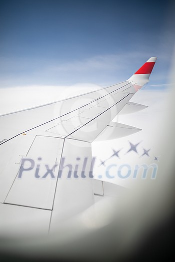 Aircraft porthole with blue sky. Looking through window aircraft during flight. Airplane wing through the porthole. Looking through window aircraft during flight