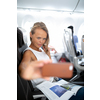 Young happy woman taking selfie photo with passport document sitting on the aircraft seat near a window during the flight in the airplane