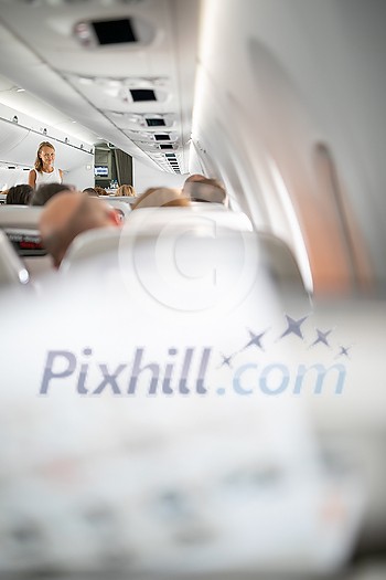 Pretty, young woman aboard an airplane during a lang haul commercial flight - stretching her legs a bit, walking in the aisle Pretty, young woman aboard an airplane during a lang haul commercial flight - stretching her legs a bit, walking in the aisle