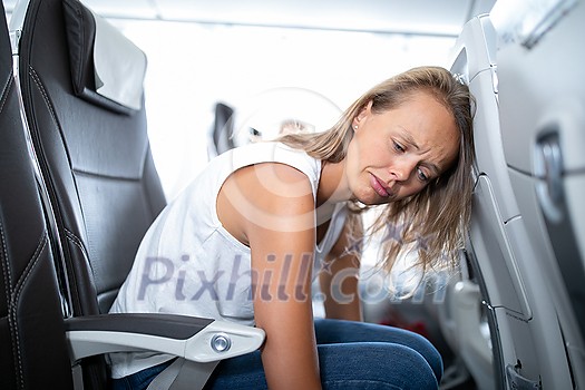 Young happy woman aboard an airplane during flight  - not feeling quite well