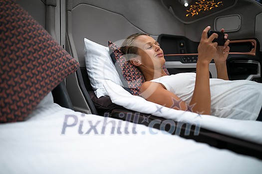 Pretty, young woman abord a first class commercial flight using their cell phone during flight