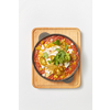 Middle eastern traditional dish Shakshuka from fried eggs with tomatoes, bell pepper, vegetables and herbs in a pan on a wooden board on a light grey background, copy space. Top view.