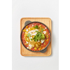 Middle eastern traditional dish Shakshuka from fried eggs with tomatoes, bell pepper, vegetables and herbs in a pan on a wooden board on a light grey background, copy space. Top view.