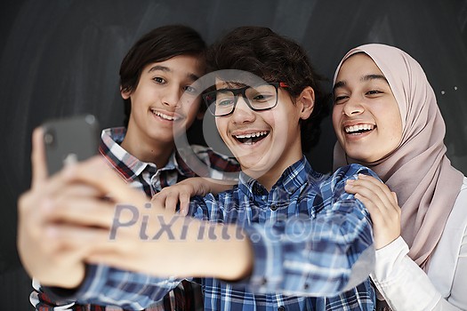 group of arab teens taking selfie photo on smart phone with black chalkboard in background group of arab teens taking selfie photo on smart phone with black chalkboard in background
