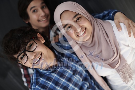 group of arab teens taking selfie photo on smart phone with black chalkboard in background